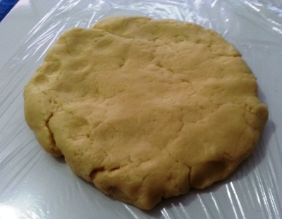 A massa sendo enrolada no papel filme para ir descansar na geladeira por 1 hora. 